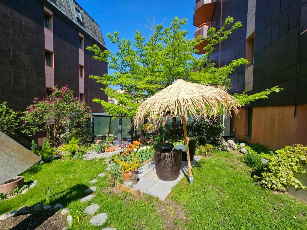 einen Garten mit einem Strohschirm und ein paar Blumen in der Unterkunft Tulip Inn Beaulieu Lausanne in Lausanne