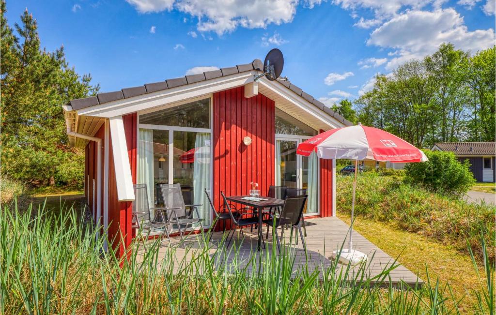 ein rotes winziges Haus mit einem Tisch und einem Regenschirm in der Unterkunft Schatzkiste 3 - Dorf 4 in Travemünde