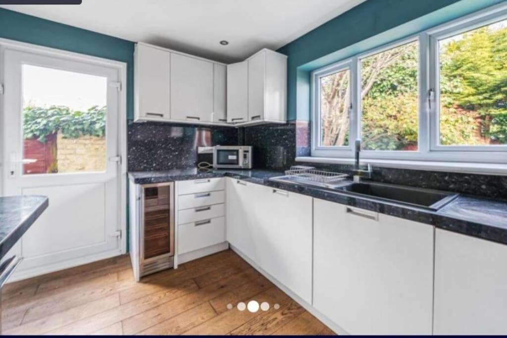 eine Küche mit weißen Schränken und einem großen Fenster in der Unterkunft cleethorpes seaside garden apartment in Cleethorpes
