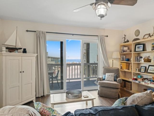 a living room with a couch and a balcony at Island North 14C - 2nd row stunner! Relax in comfort after your days in the sun condo in Carolina Beach