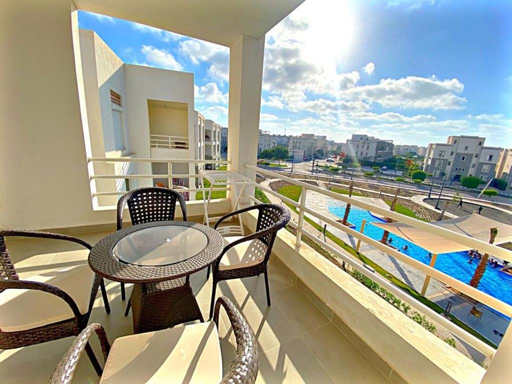 a balcony with a table and chairs and a pool at Amwaj North Coast Q zone Second floor in El Alamein