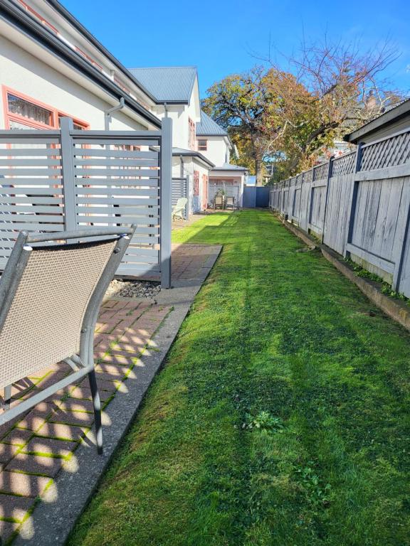 a bench sitting in the grass next to a fence at ASURE Destiny on Fitzherbert Motel in Palmerston North