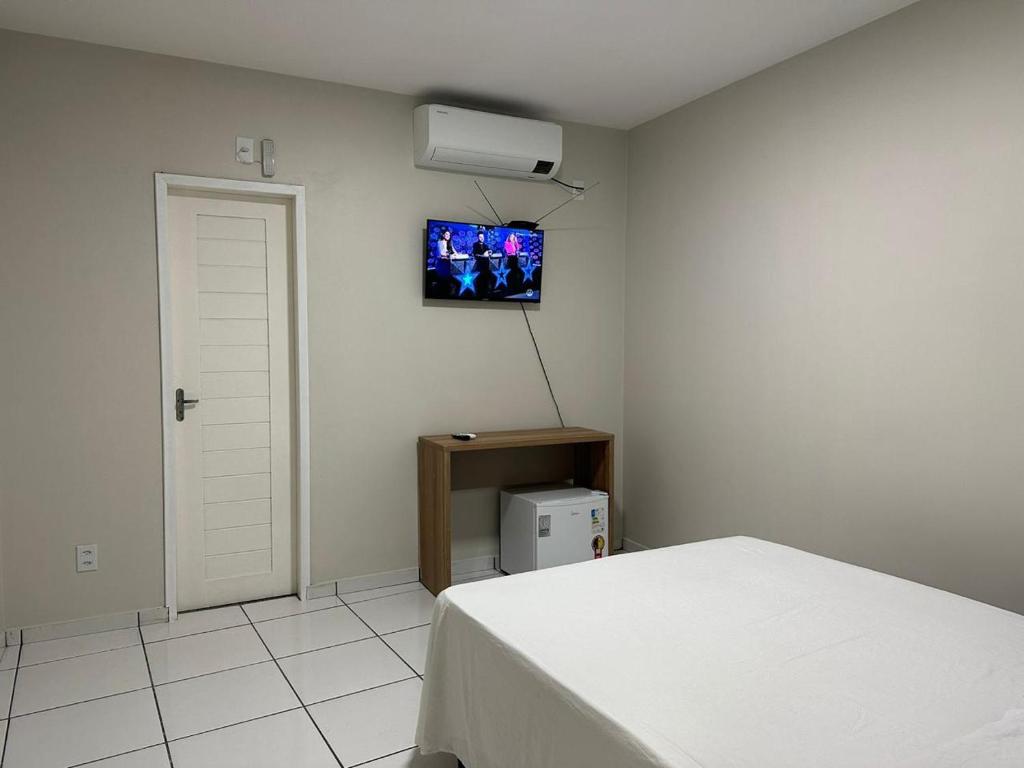1 dormitorio con 1 cama y TV en la pared en Pousada Central dos Lençóis en Barreirinhas