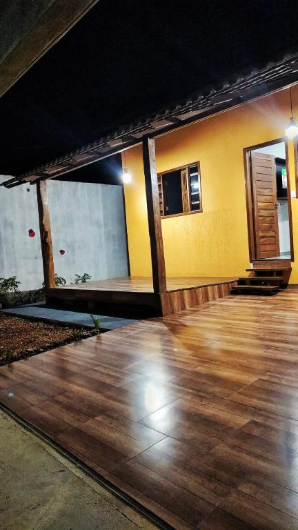 a room with a wooden floor and a yellow wall at Casa temporada Flor de pitanga in Cavalcante