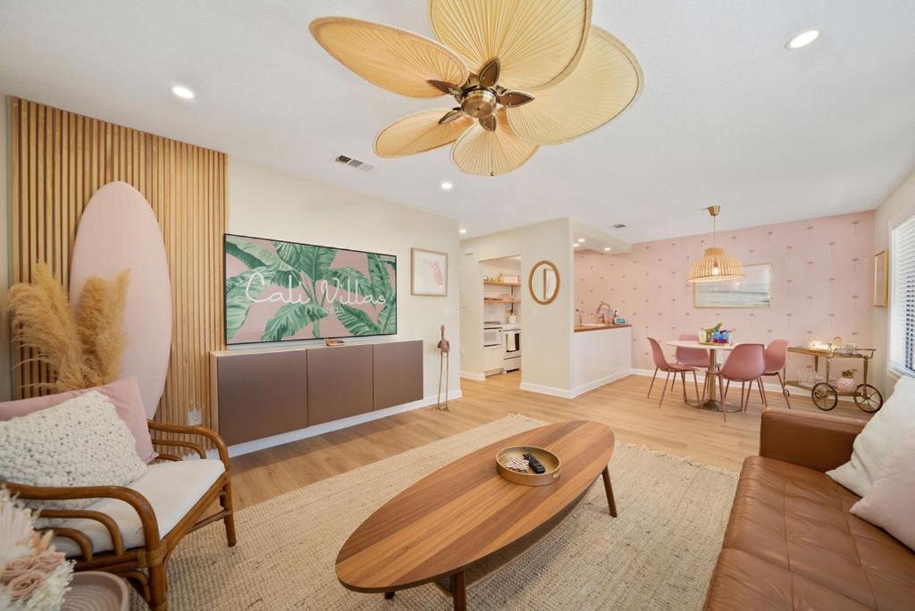 a living room with a ceiling fan and a table at Luxury Villa 3 Blocks from the Beach with Pool a Fire Pit and Outdoor Oasis in Cape Canaveral