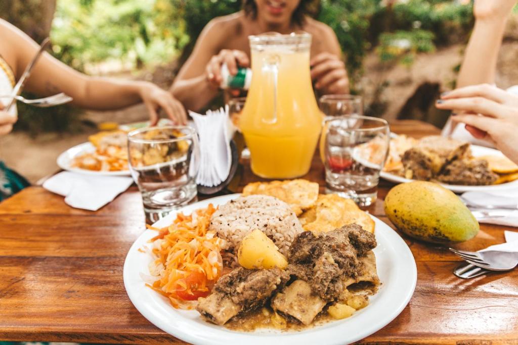 Cabaña Wiwa Tayrona في سانتا مارتا: طاولة بها طبق من الطعام والناس جالسين حوله