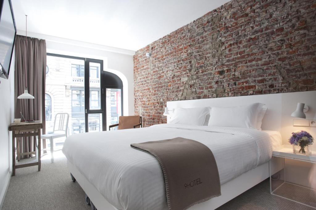 een slaapkamer met een groot bed en een bakstenen muur bij 9Hotel Central in Brussel