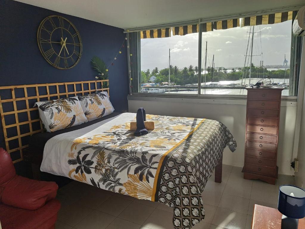 - une chambre dotée d'un lit avec une horloge murale dans l'établissement Superbe appartement au coeur de la Marina, à Pointe-à-Pitre