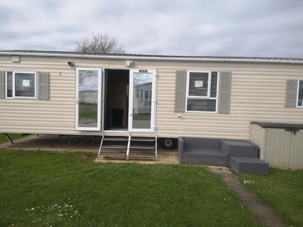 a mobile home with a porch and a couch in a yard at The Powers in Rhyl