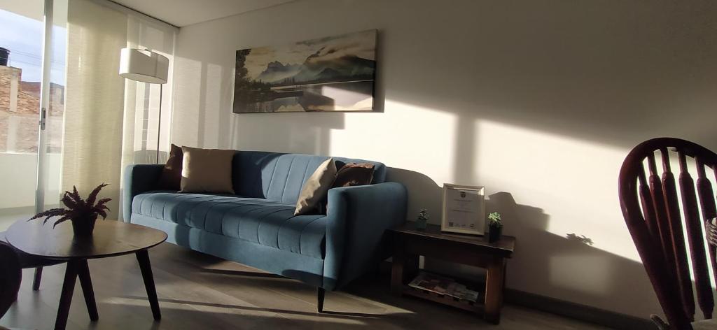 sala de estar con sofá azul y mesa en Amplio apartamento lujoso al lado del lago, en Paipa