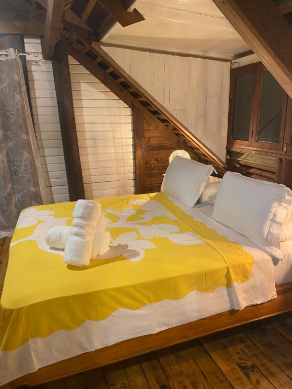 - une chambre avec un lit jaune et des serviettes dans l'établissement Great House BY Manaeva Lodge, à Temae