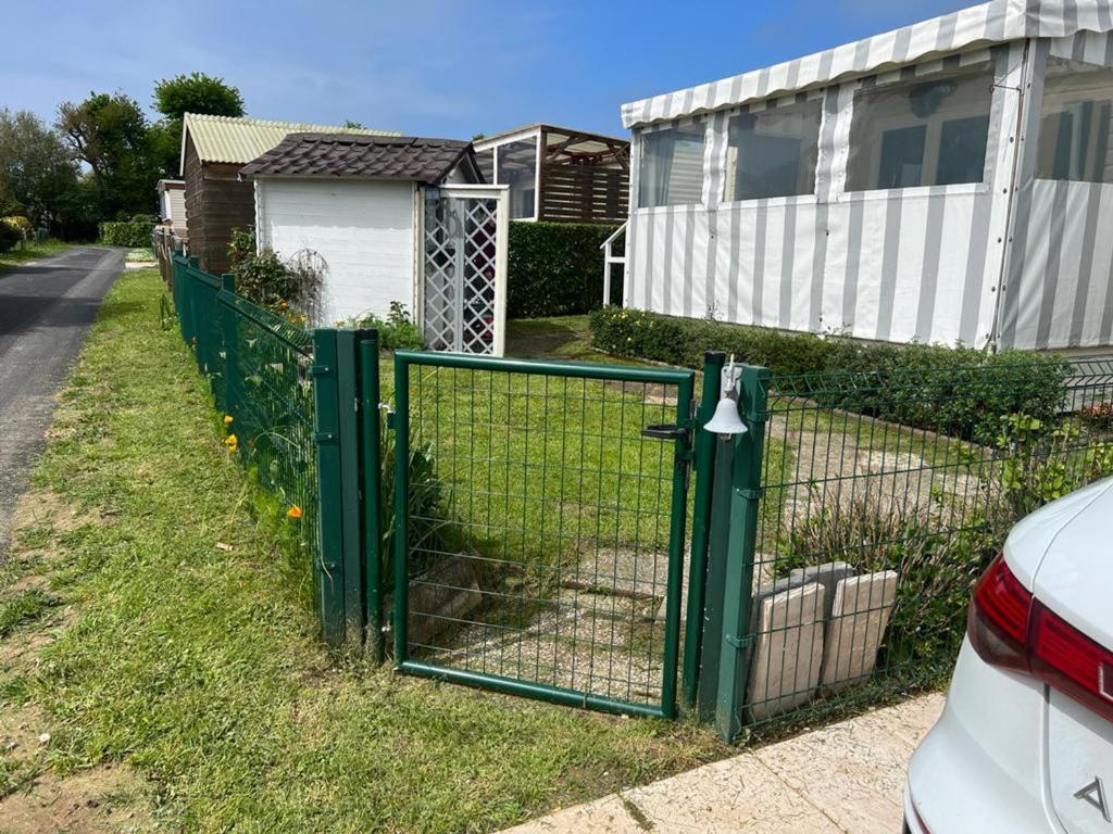 un cancello verde nell'erba vicino a una casa di Mobil-Home Blonville-sur-Mer, 3 pièces, 6 personnes - FR-1-712-60 a Blonville-sur-Mer