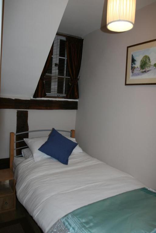 a bed with a blue pillow in a room at Peel Cottage, Dilwyn in Dilwyn