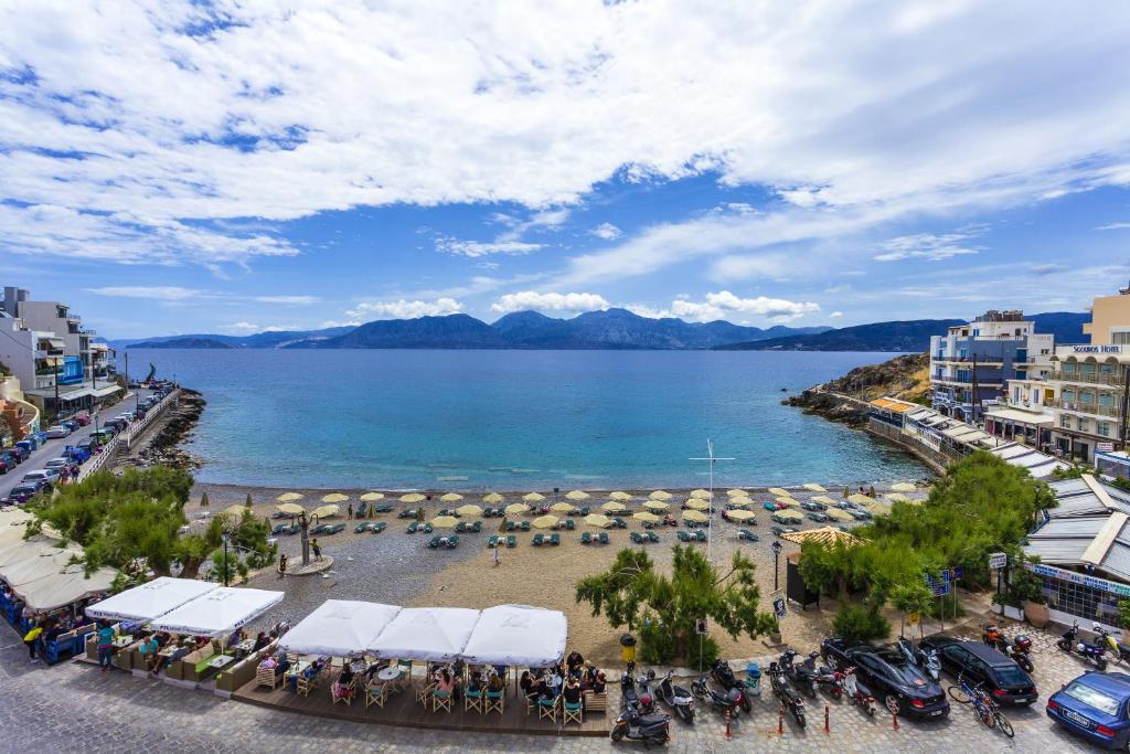 einen Strand mit Sonnenschirmen und einem Körper aus Wasser in der Unterkunft Palazzo Arhontiko Apartments in Agios Nikolaos