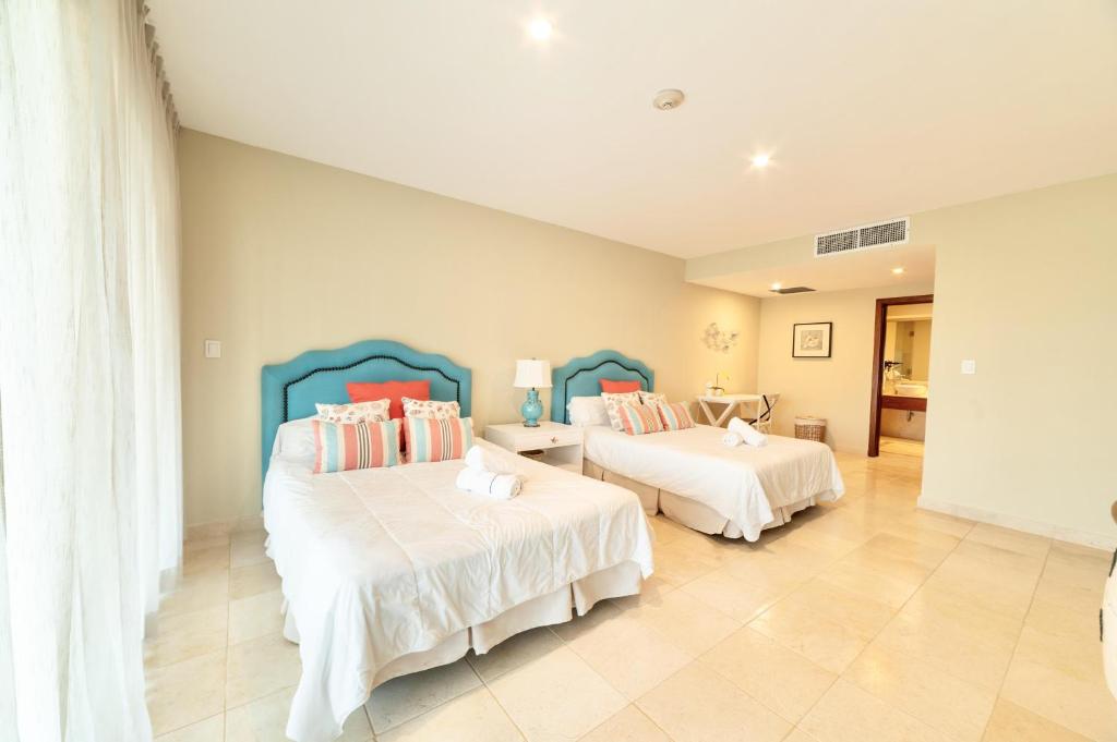 a bedroom with two beds with white sheets at New! Beachfront Lux Condo With Private Jacuzzi in Punta Cana