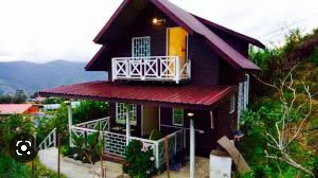 a small house with a red roof and a balcony at Rania Lovely Hut Homestay Kundasang in Kampong Kundassan
