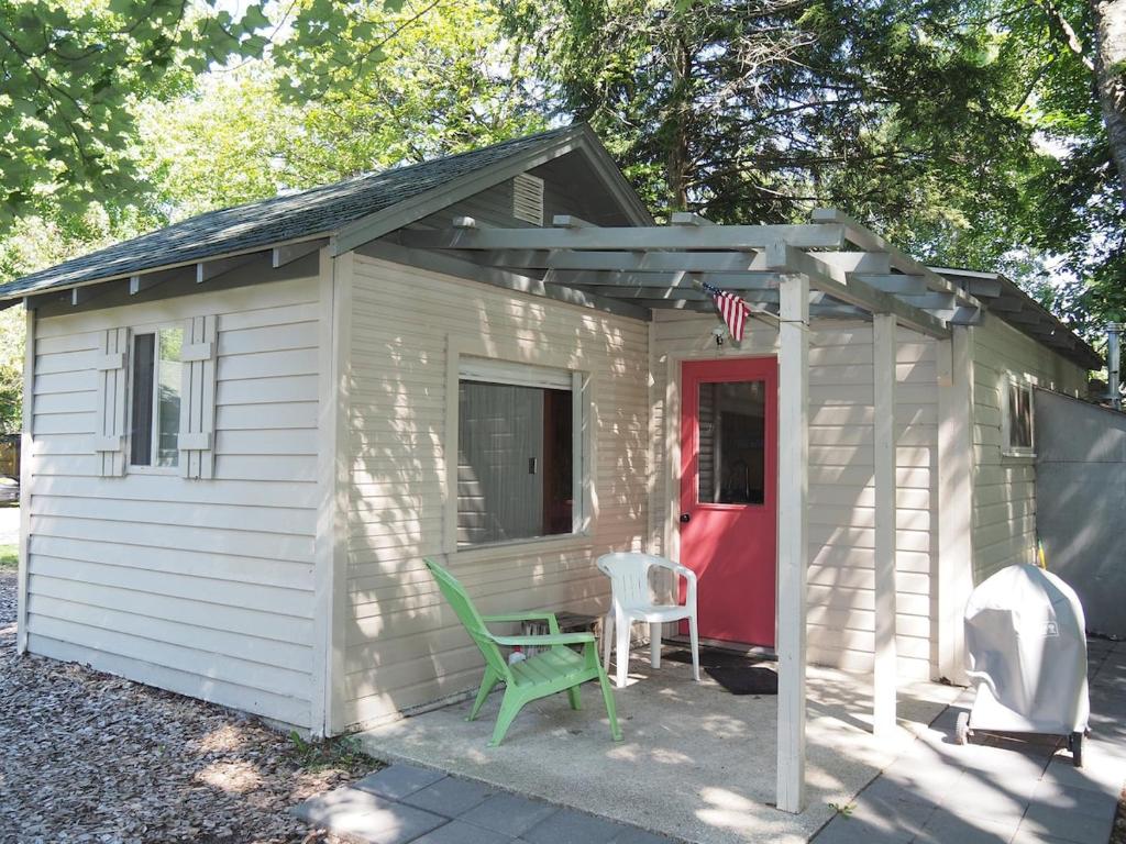 cobertizo blanco con puerta roja y silla verde en Sleeping Bear Riverside Cabins - Cabin #4, en Honor