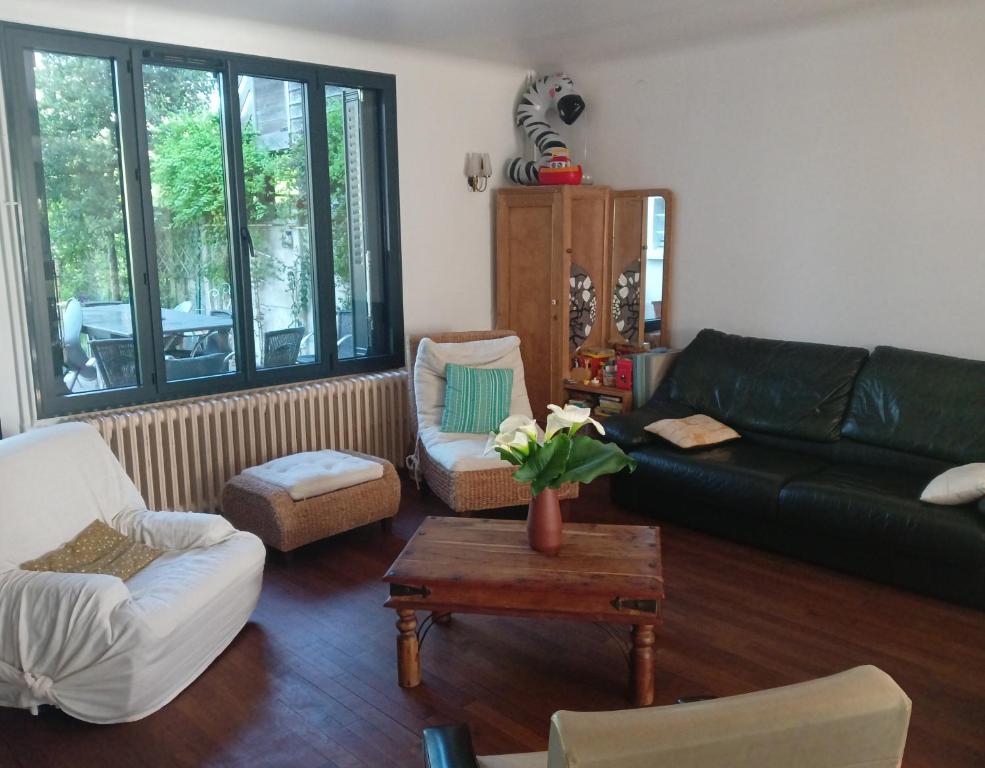 una sala de estar con un sofá de cuero negro y sillas en Chez Agathe et Mathieu en Le Mans