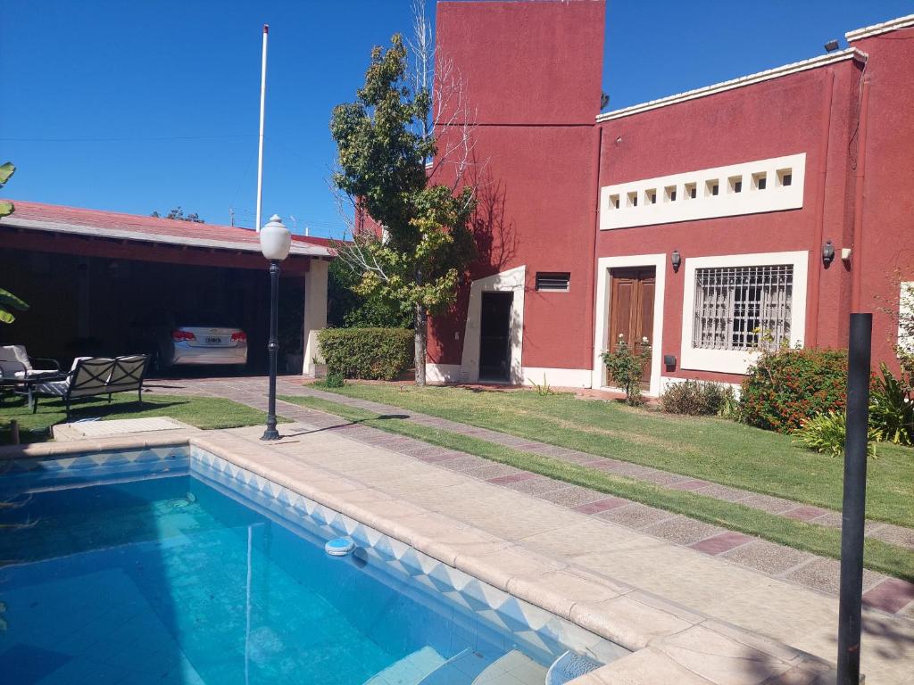 a swimming pool in front of a red building at Habitación con baño privado y estacionamiento in San Martín