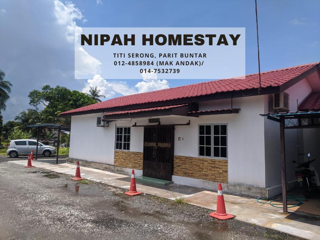Nipah Homestay Parit Buntar في باريت بونتار: مبنى أمامه مخاريط برتقالية