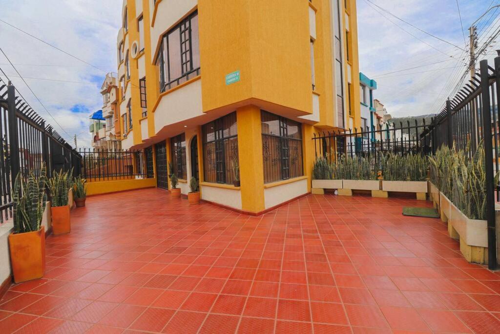 un gran edificio amarillo con un patio de azulejos rojos en Apto duplex mandarina 2 niveles jardín y parqueo privado!, en Sogamoso