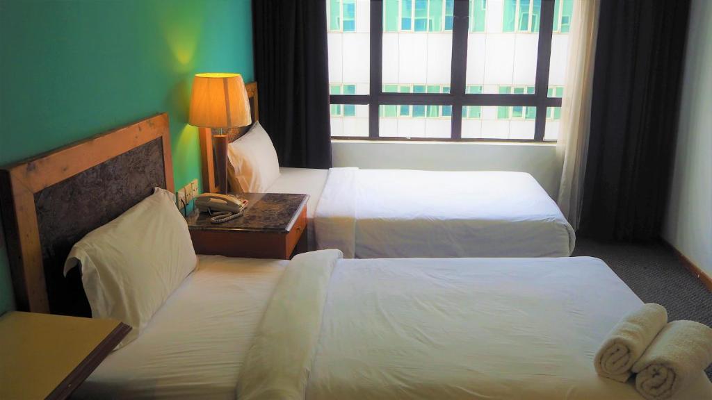 a hotel room with two beds and a window at WTC Hotel, Kuala Lumpur - Formerly Leo Palace Hotel Classic Wing in Kuala Lumpur