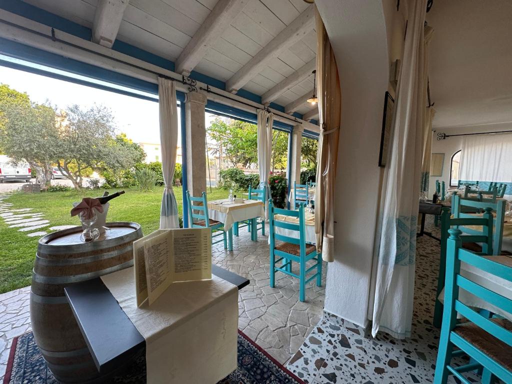 une terrasse avec des chaises bleues et une table avec un vase dans l'établissement Hotel S'Ortale, à Orosei