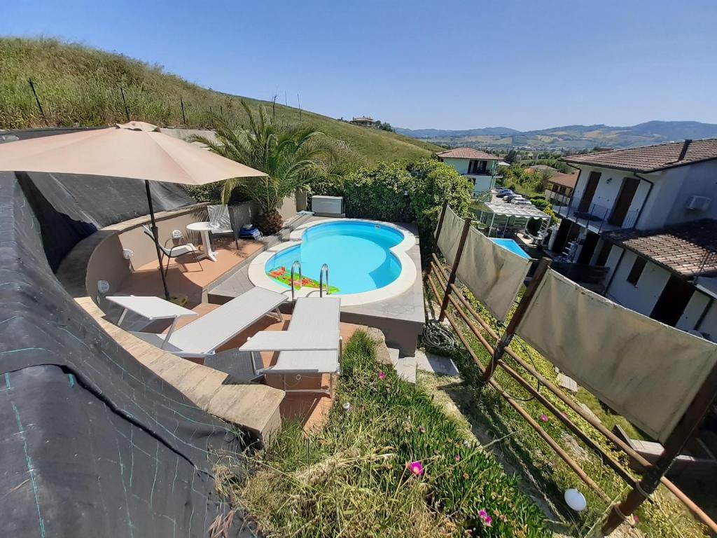 a swimming pool with an umbrella and some chairs and an umbrella at Holiday home Tavullia in Tavullia