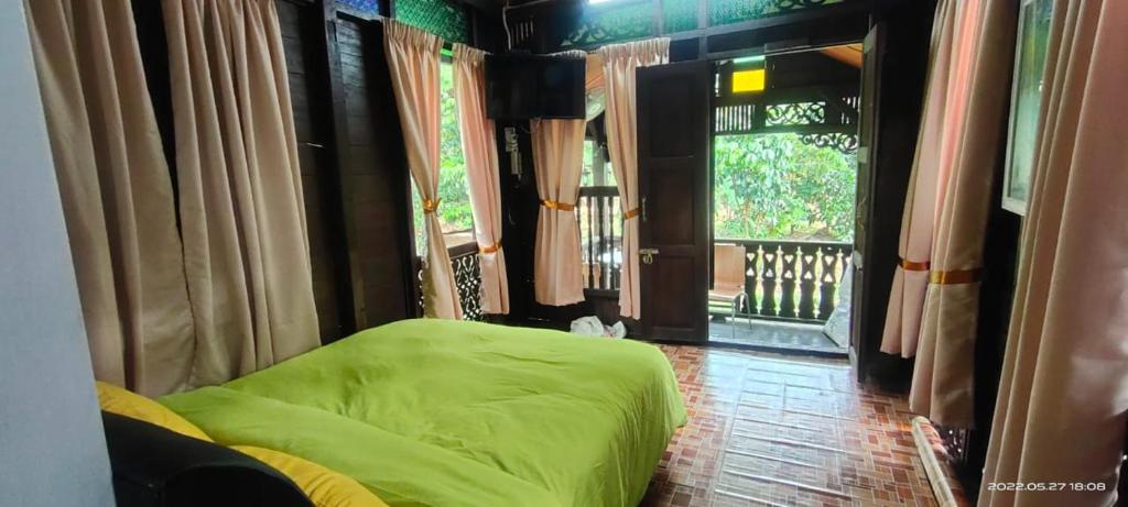 a bedroom with a green bed and a window at SRI MALAU 