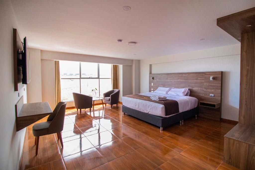 een slaapkamer met een bed en een tafel en stoelen bij Hotel Cumbre Real Airport - Arequipa in Arequipa