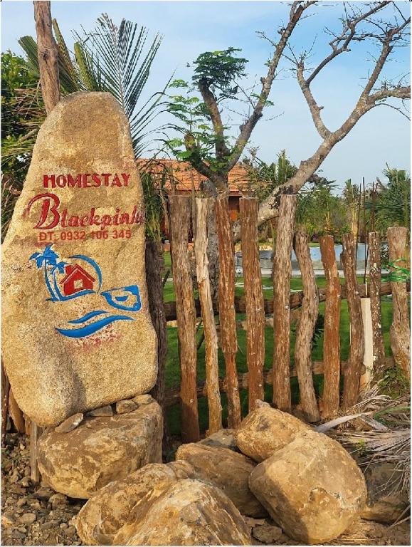 a large rock sitting next to a wooden fence at BlackPink Homestay Hồ Tràm in Xóm Trương Quít