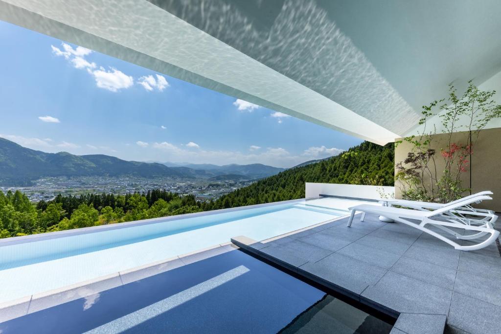a villa with a infinity pool and a chair at ENOWA in Yufuin