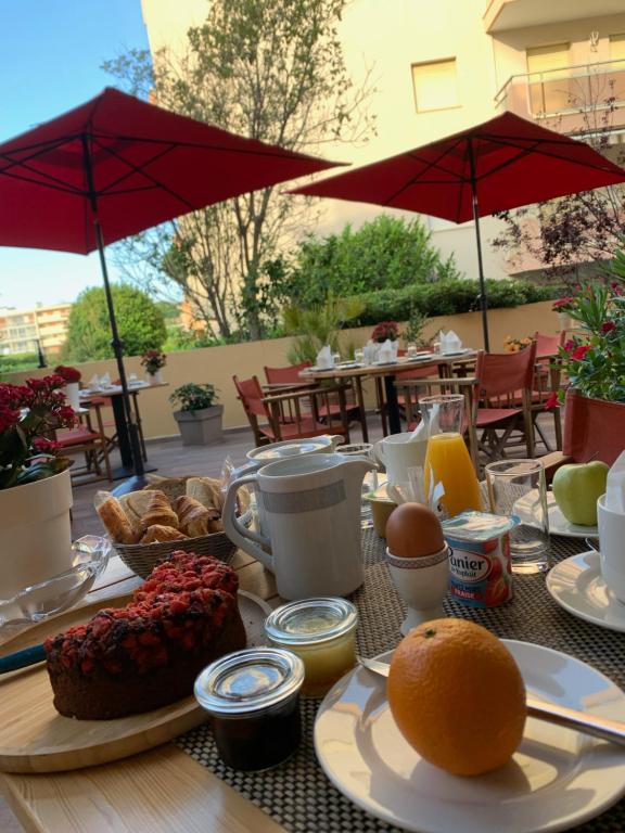 een tafel met ontbijtproducten op een tafel met parasols bij Le Petit Prince in Sainte-Maxime