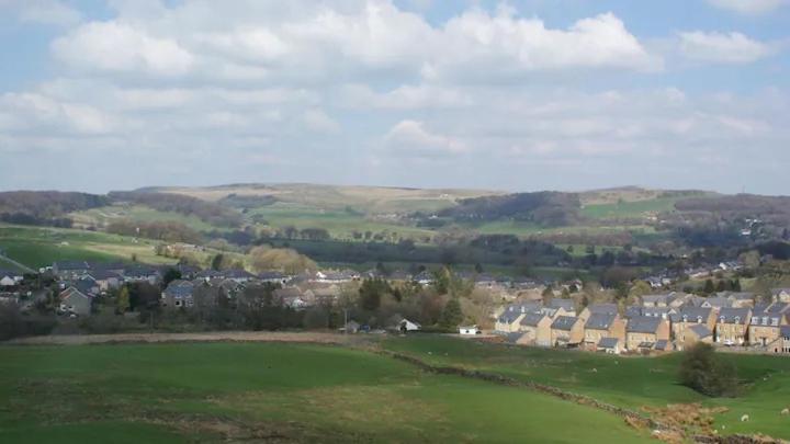 a green field with houses and a town in the distance at Bridge Farm Caravan in Buxton