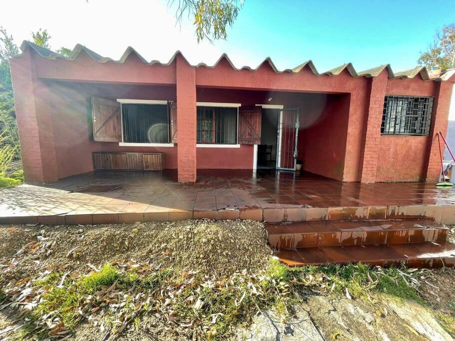 una pequeña casa roja con lluvia en Casa Alquiler Cuchilla Alta 2 en Cuchilla Alta