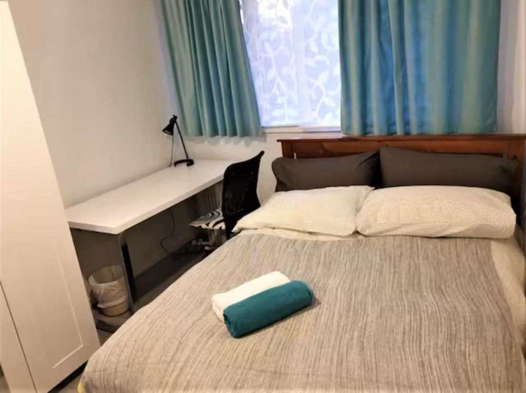 een slaapkamer met een groot bed met een groen kussen erop bij Private Room in a Shared House-Close to City & ANU-2 in Canberra