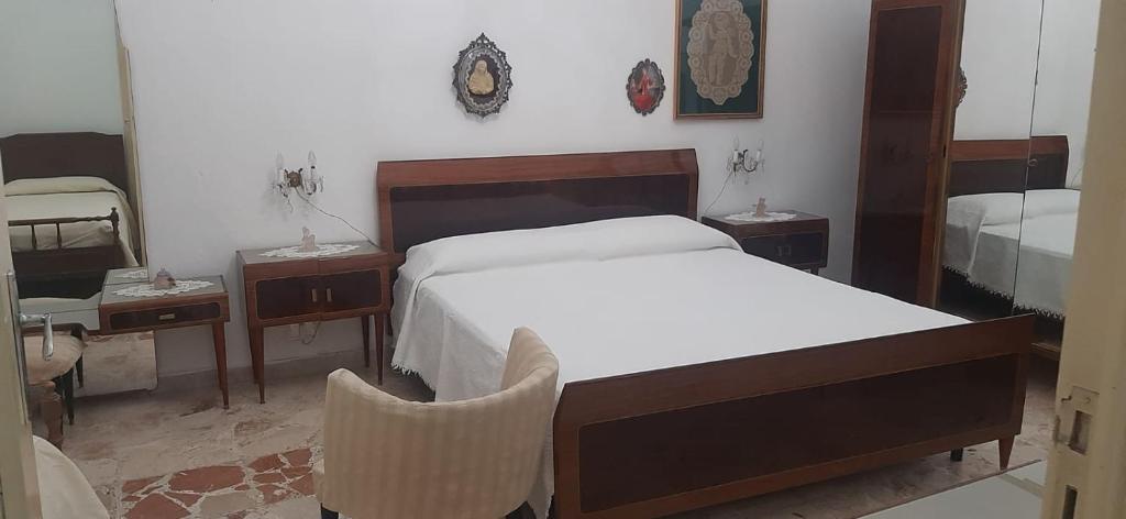 a bedroom with a bed and two tables and a chair at Casa della nonna Marina in Floridia