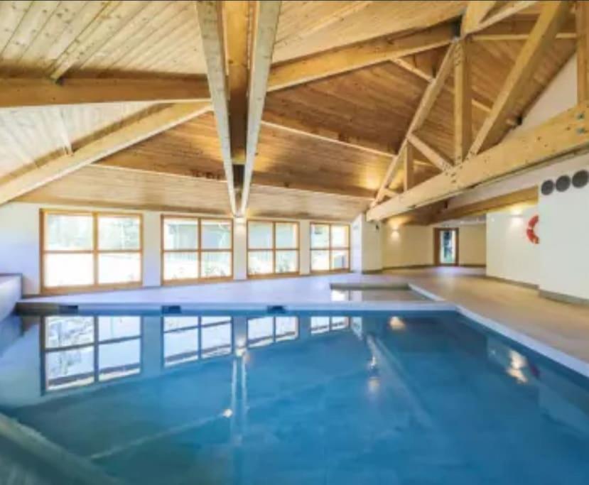 a large swimming pool in a large room with wooden ceilings at Appart 8 personnes piscine sauna pied des pistes in Le Dévoluy