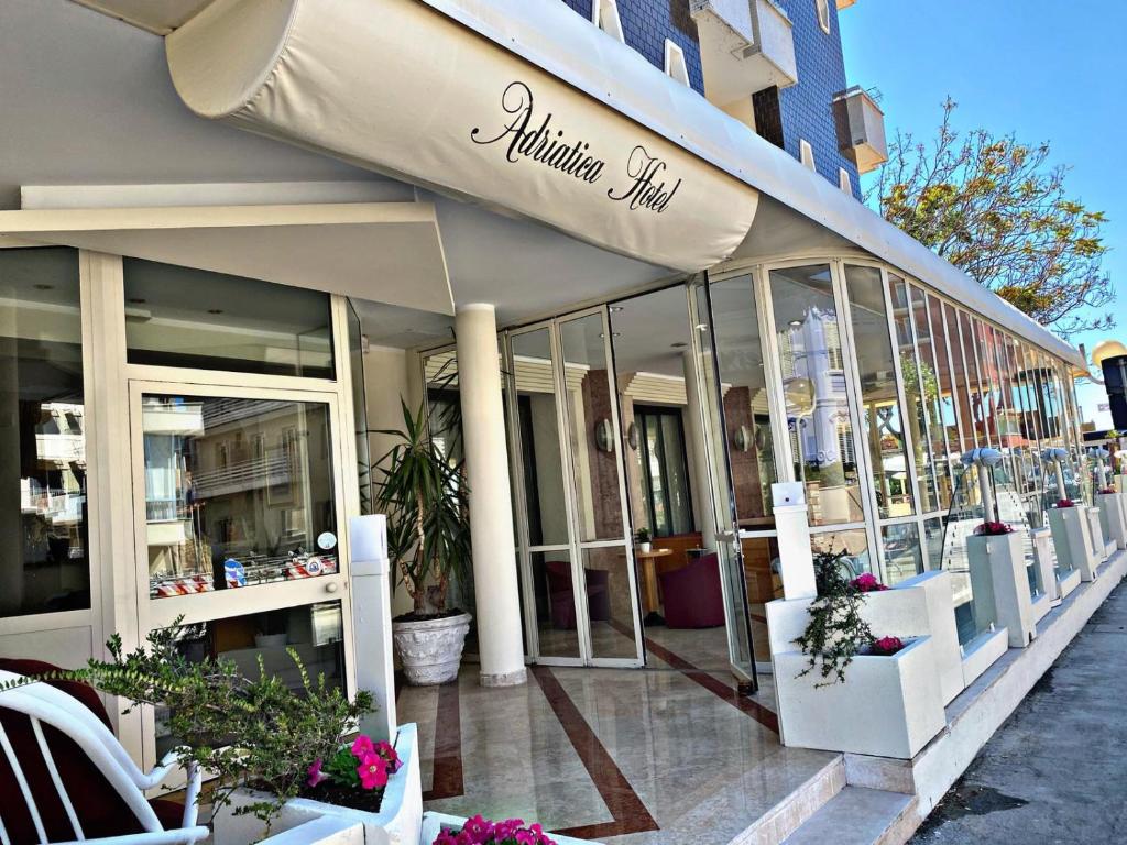 uma loja na frente de um edifício com janelas e plantas em Hotel Adriatica sul Mare em Rimini