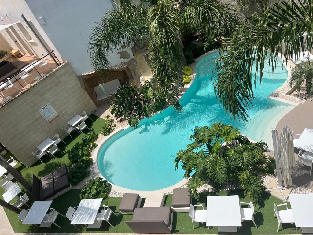 - une vue sur la piscine bordée de chaises et de palmiers dans l'établissement Tra le nuvole, à Favignana