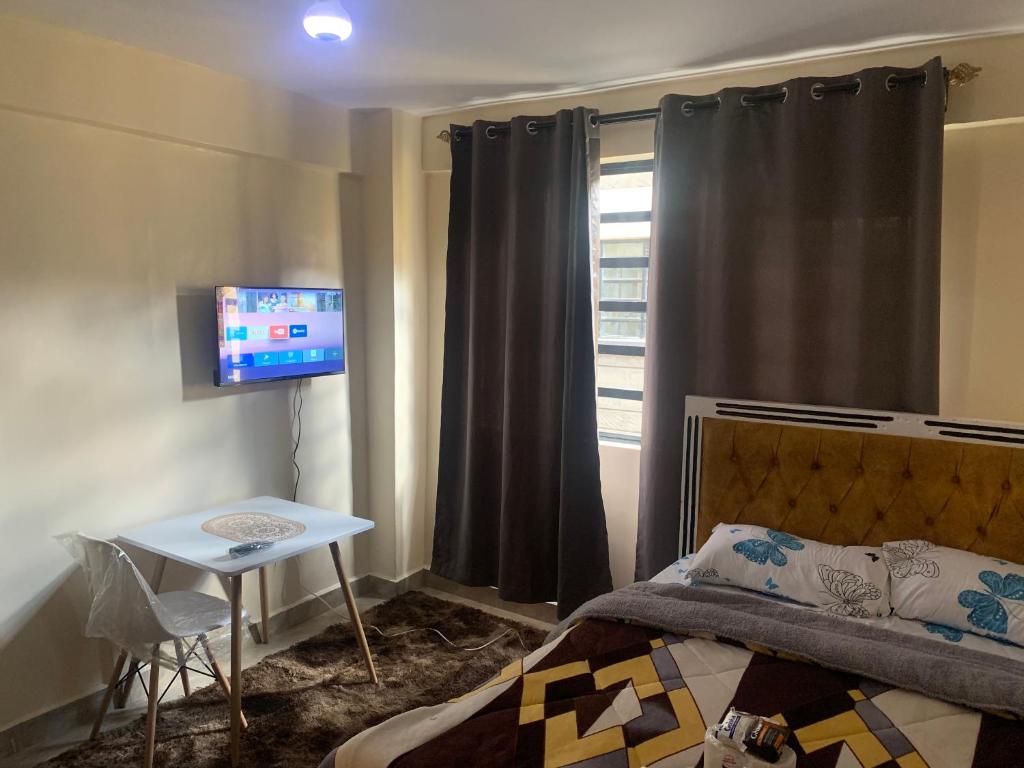 ナイロビにあるgold-apartment-and-luxury-homeのベッドルーム(ベッド1台、テーブル、テレビ付)