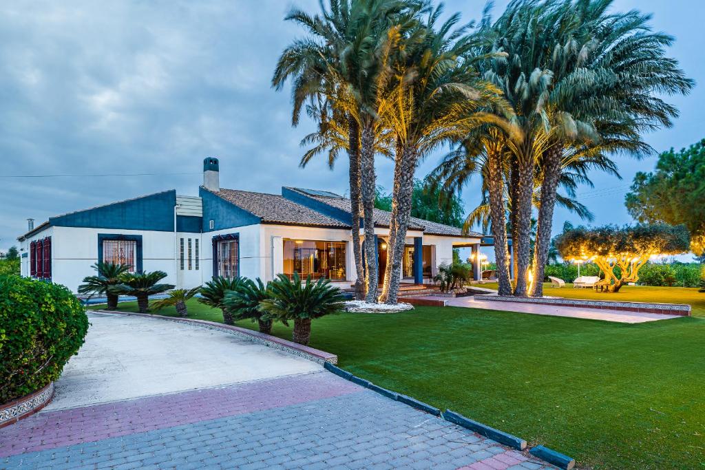 una casa con palmeras y un camino de entrada en El Bancalito Suites and Garden, en Los Montesinos