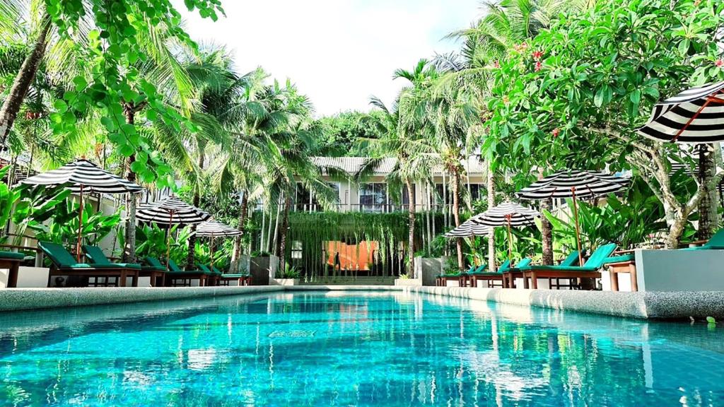 a swimming pool with chairs and umbrellas at Signature Phuket Resort SHA Plus in Chalong