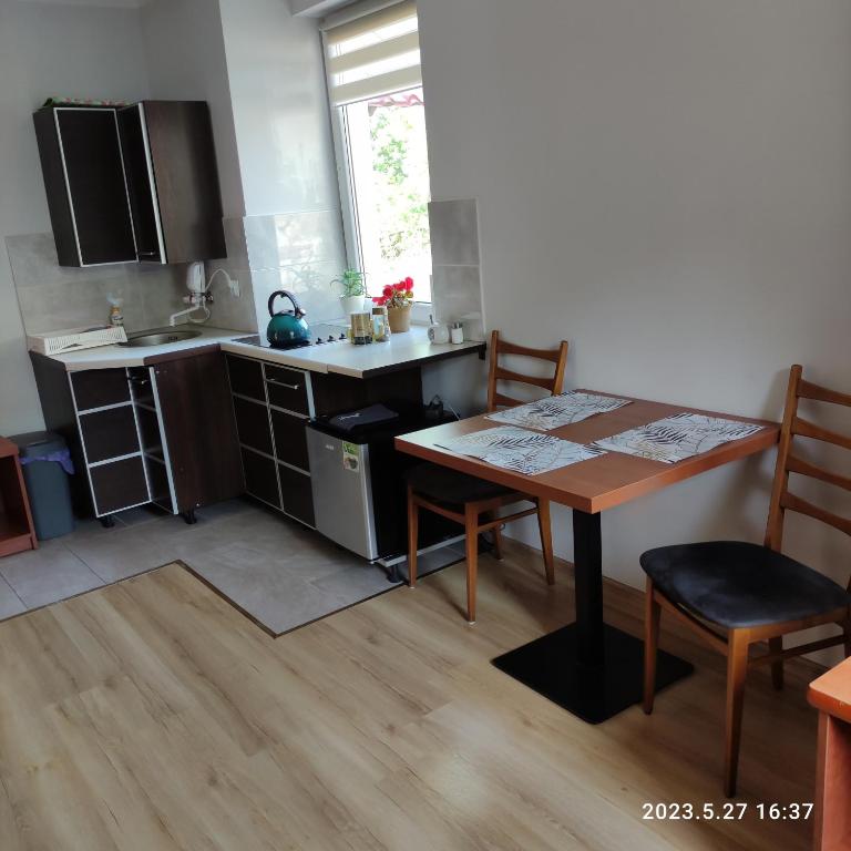 eine Küche mit einem Holztisch sowie einem Tisch und Stühlen in der Unterkunft Apartament pod Lipą in Kłodzko