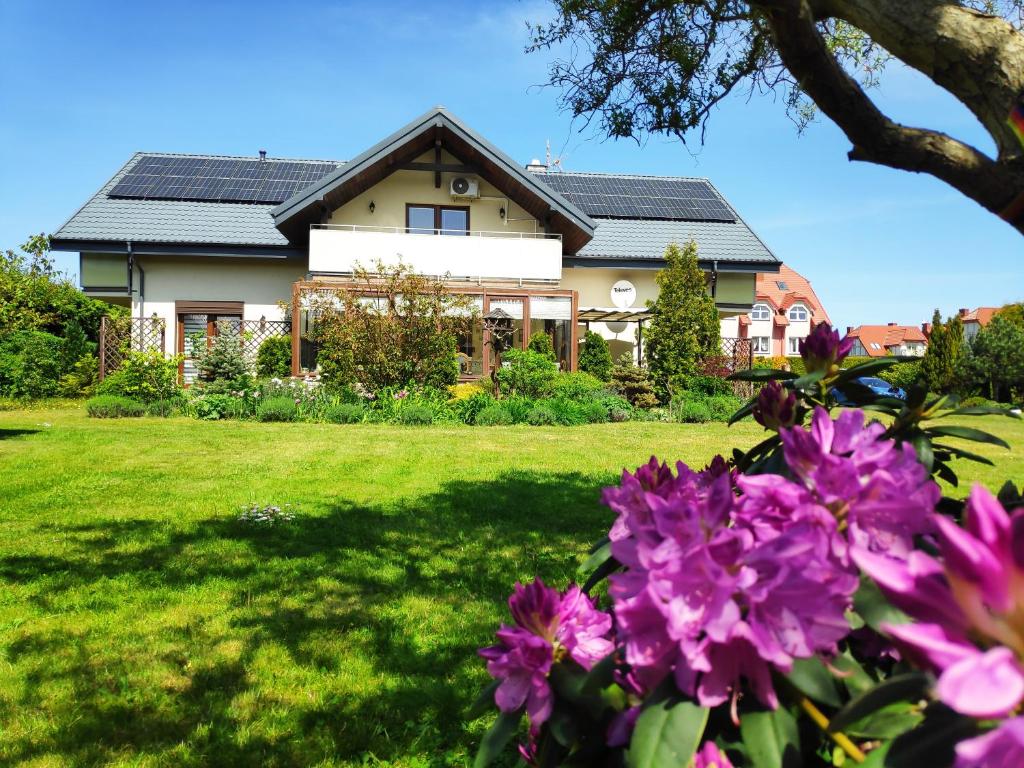 a house with some purple flowers in the yard at Villa NOVA Dębki in Dębki