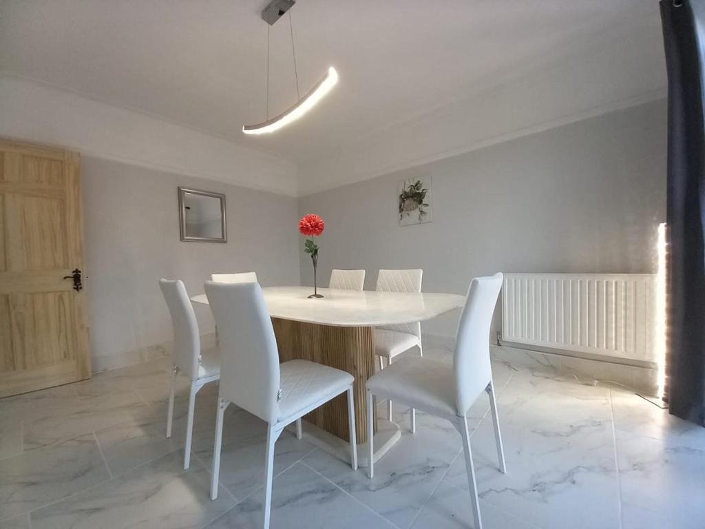 a dining room with a white table and white chairs at Peaceful Home in Surbiton, Surrey, Greater London- Free parking in Surbiton