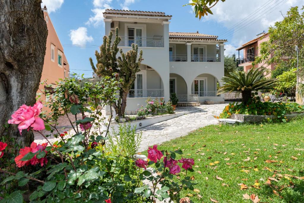 una grande casa bianca con fiori in cortile di Averto Corfu Apartments a Dassia