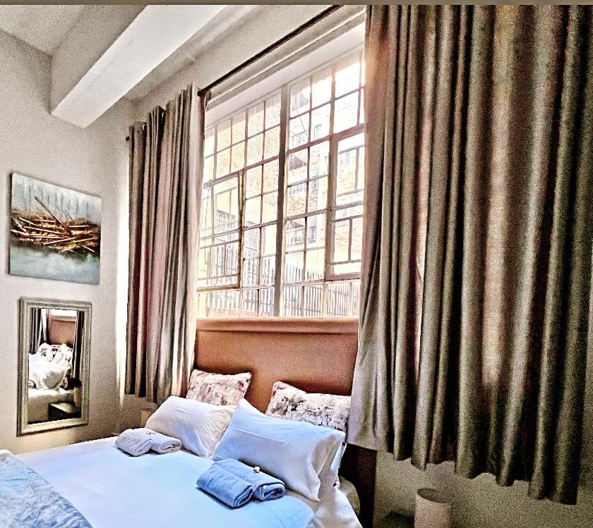 1 dormitorio con cama y ventana grande en Mocha Apartment next to Maboneng, en Johannesburgo