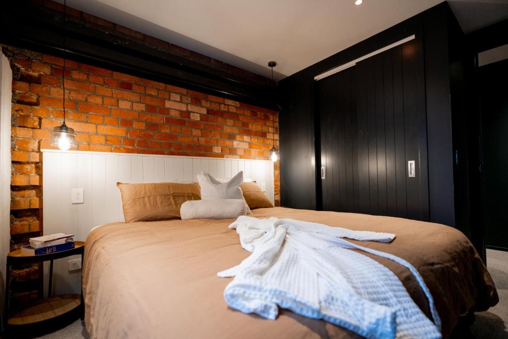 a bedroom with a bed and a brick wall at The Cobbler Hotel in Wellington