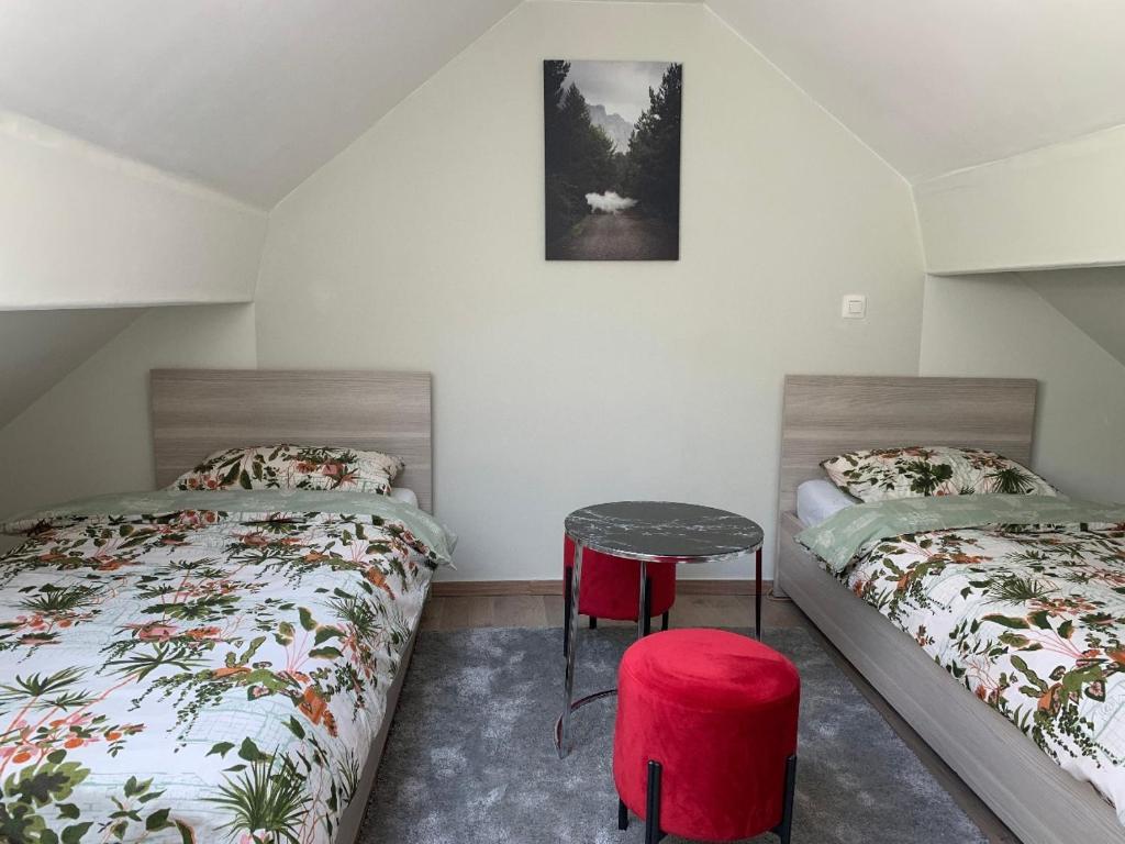 1 dormitorio con 2 camas, mesa y taburete en Un sommeil paisible, en Bruselas